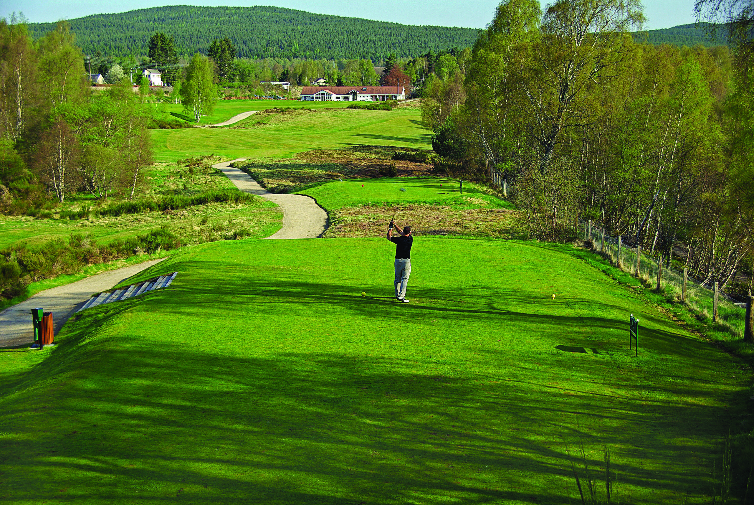 Boat of Garten Golf Club fairways framed by pine trees and the Cairngorm Mountains in the background.